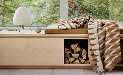 Panca da interno, con un cuscino, una lampada e una coperta