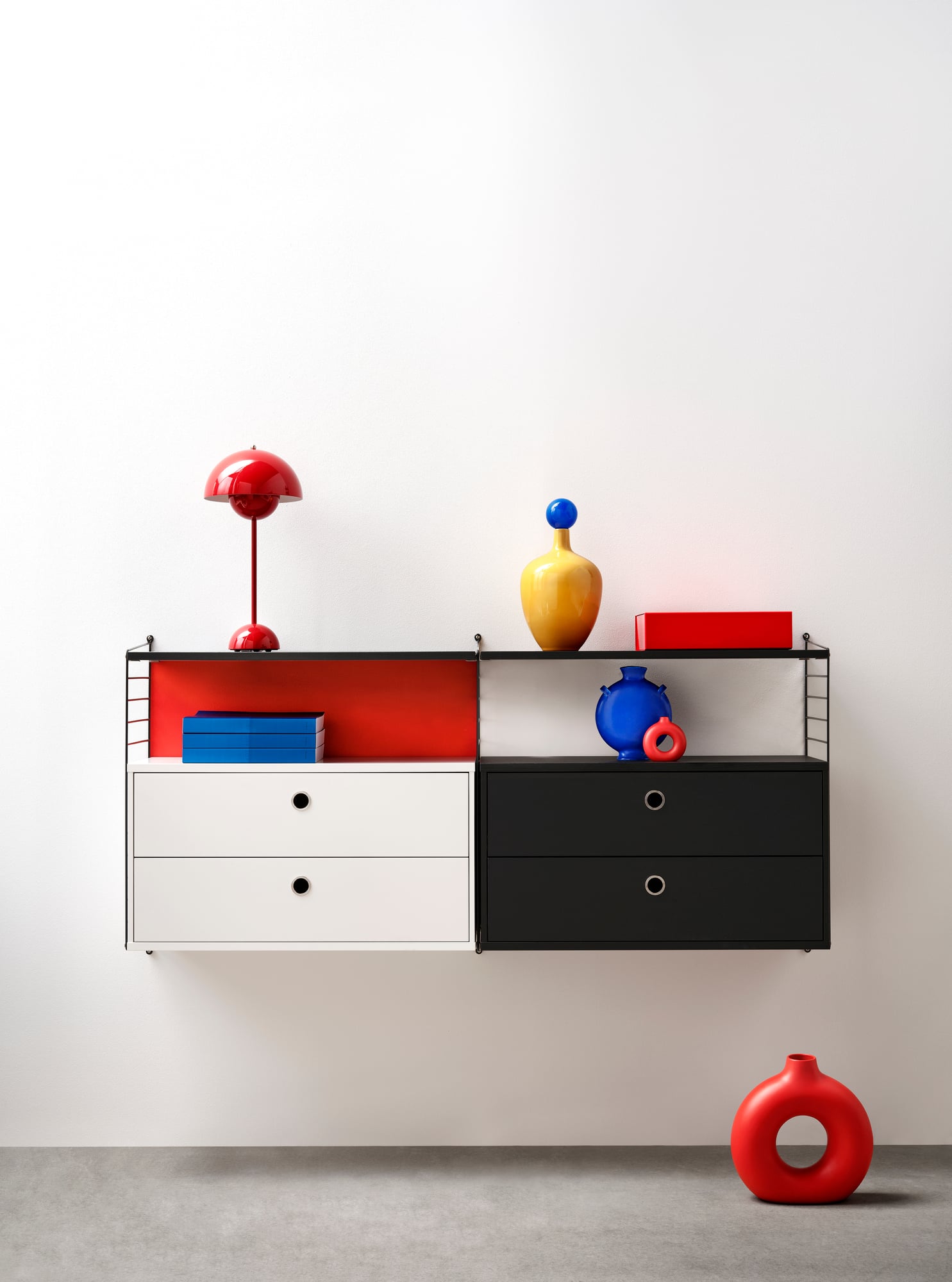 Wall shelf unit with white drawers and black cabinets against a white wall.