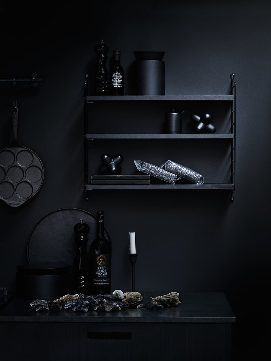 Black metal wall shelf with bar and kitchen items.
